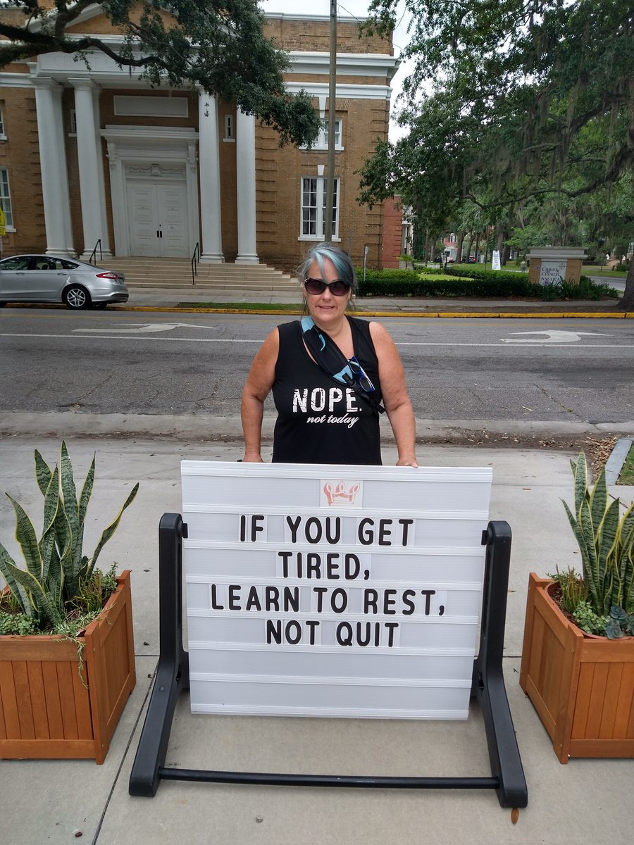 Marley Gibson with Learn to Rest Not Quit sign in Savannah